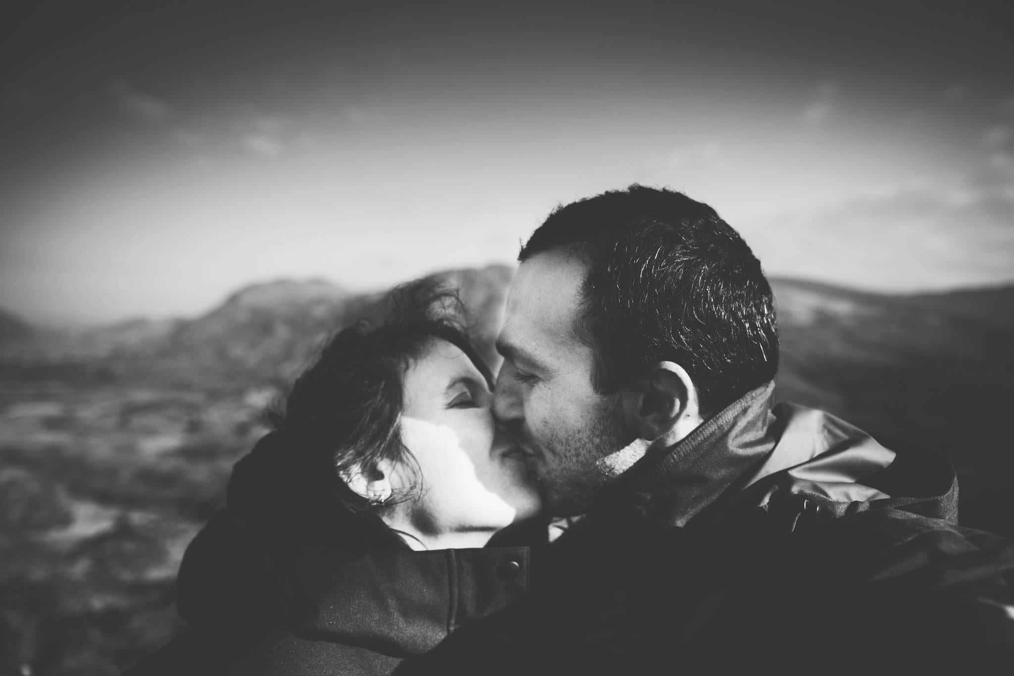 A man and a woman kissing whilst on a romantic campervan holiday in Ireland