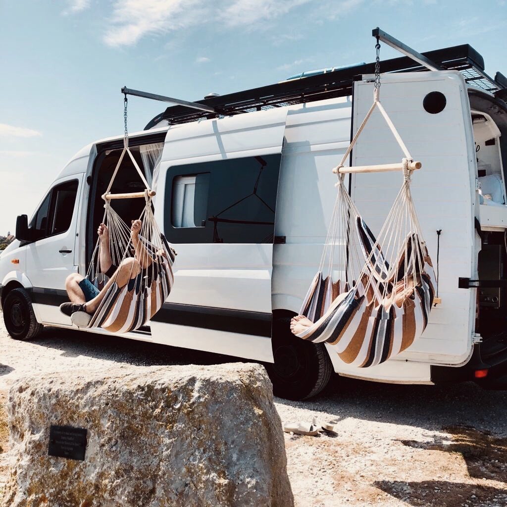 Swinging from hammocks in front of a campervan