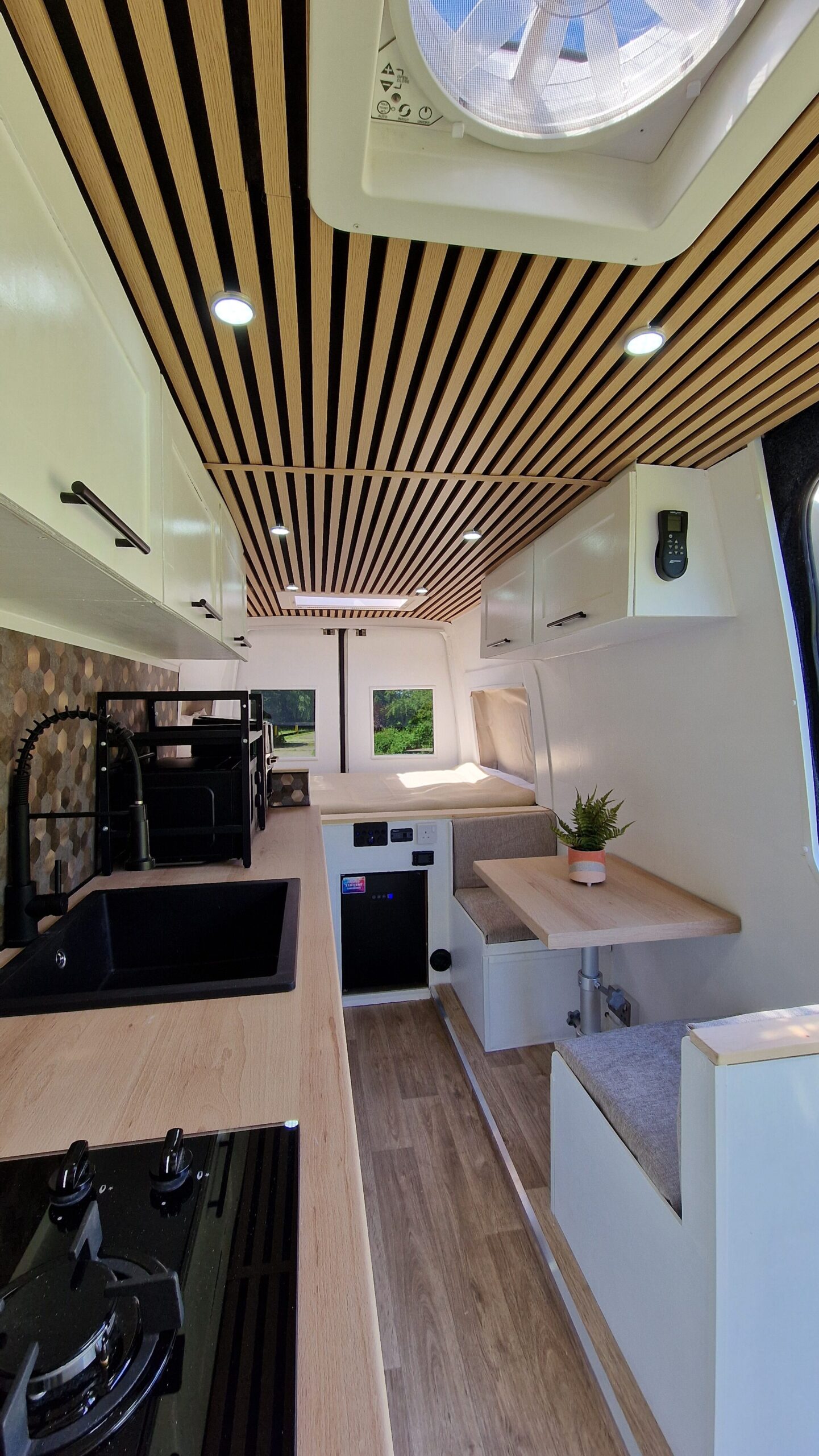 inside of the van, white interior with wood, black kitchen appliances, air vent