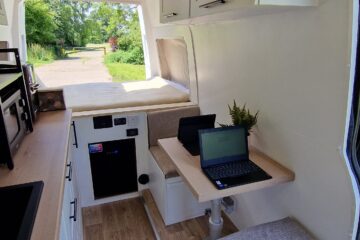 inside of the van, white walls, stunning interior, seating and a bed.