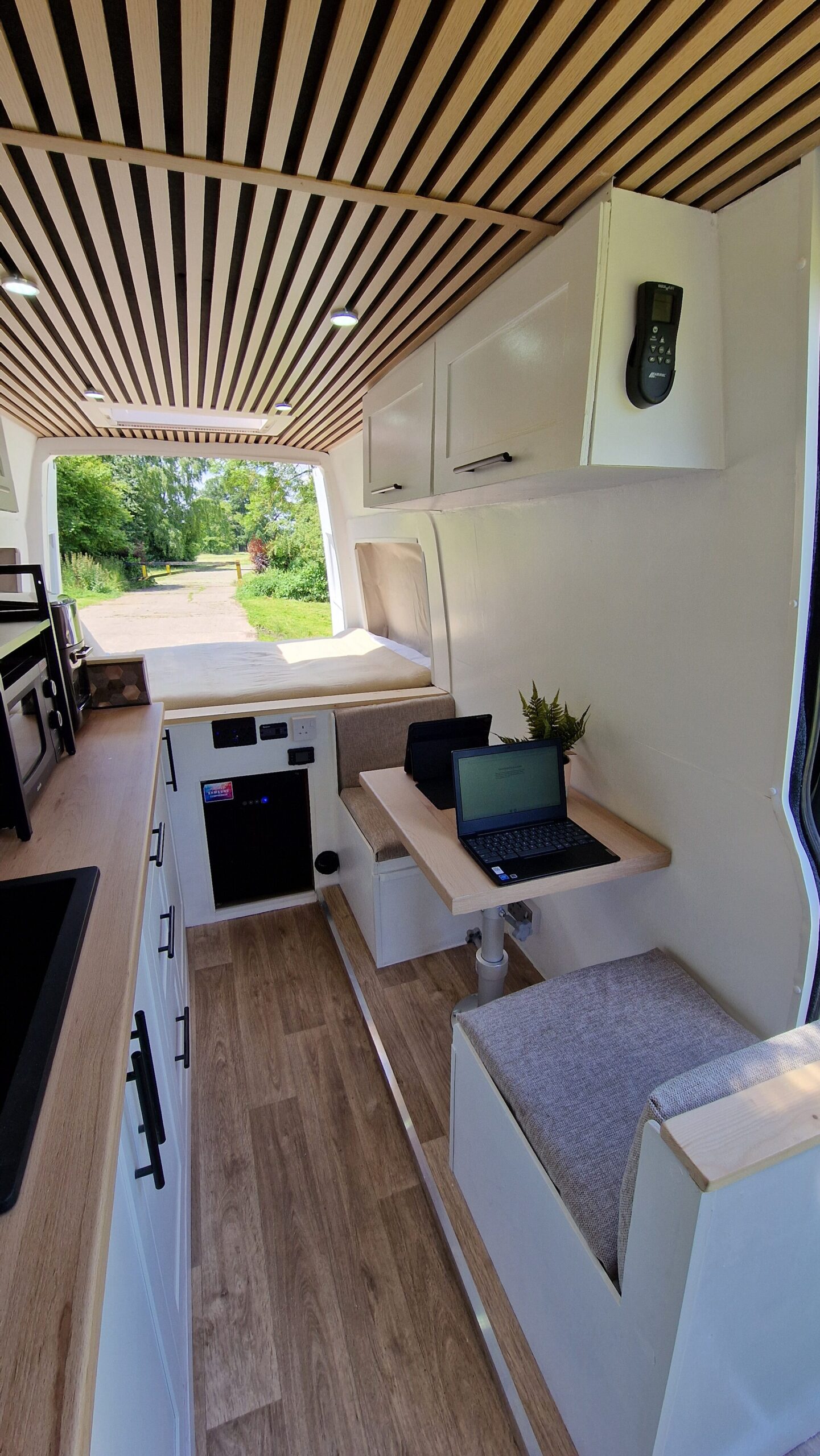 inside of the van, white walls, stunning interior, seating and a bed.